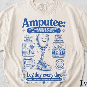May include: Ivory-colored t-shirt with a blue graphic that reads "Amputee: Not All Parts Included, All Heart Included." The design includes an illustration of a prosthetic leg, a coffee mug, and other motivational images. The text "Leg day every day" is also included.