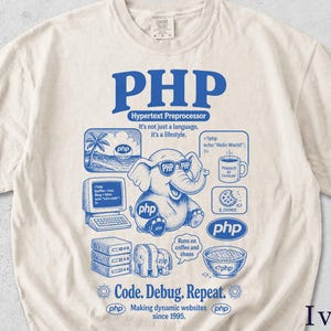 May include: An ivory t-shirt featuring a blue graphic print. The design includes a central elephant wearing sunglasses, a computer, a coffee mug, a bowl of cereal, and text including PHP, Hypertext Preprocessor, It's not just a language, it's a lifestyle, Runs on coffee and chaos, and Code. Debug. Repeat.