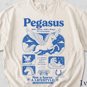 Może przedstawiać: Koszulka w kolorze kości słoniowej z niebieskim nadrukiem graficznym przedstawiającym uskrzydlonego konia. Tekst głosi: Pegasus, 100% Horse. 100% Wings. 0% Grounded. Born fabulous. Stays fabulous. Still no interest in your drama. Not a horse. A LIFESTYLE. Powered by Awesomeness.