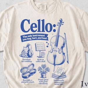 May include: Ivory t-shirt featuring a blue cello graphic and text. The design includes a cello, cat, musical notes, and the words "Cello: The only instrument you hug, hurt, and haul."