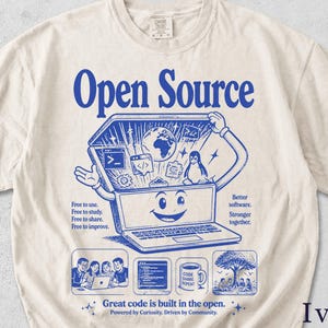 May include: An ivory t-shirt featuring a blue graphic print. The design shows a smiling laptop character with icons of a globe, code, and a penguin. Text includes "Open Source," "Free to use," "Better software," and "Great code is built in the open."