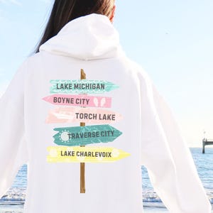 May include: White hooded sweatshirt with a graphic of a wooden signpost with arrows pointing to different Michigan towns: Lake Michigan, Boyne City, Torch Lake, Traverse City, and Lake Charlevoix.