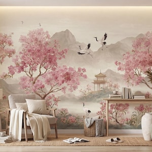 May include: A wall mural featuring a landscape with pink flowering trees, flying cranes, and a pagoda structure set against distant mountains. The scene is rendered in soft, muted tones, covering the entire wall behind a chair and a wooden table.