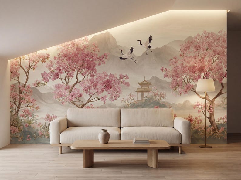 May include: A wall mural featuring a landscape with pink cherry blossom trees, two flying cranes, and a pagoda structure set against distant mountains. The scene is rendered in soft, muted tones, providing a backdrop for a beige sofa and coffee table.