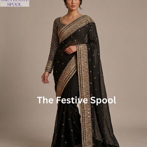 Puede incluir: Sari negro con bordados y adornos dorados. La blusa de manga larga y el borde presentan detalles intrincados. El logotipo de The Festive Spool es visible en la parte superior izquierda y el texto "The Festive Spool" en la parte inferior.