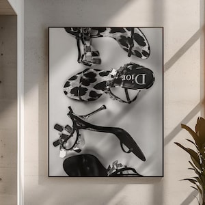 Könnte beinhalten: Schwarz-Weiß-Fotografie von drei Paar High Heels. Ein Paar hat einen Leopardenmuster, die anderen sind einfarbig schwarz. Das Dior-Logo ist auf einem Schuh sichtbar. Das Bild ist in einem schwarzen Rahmen dargestellt.