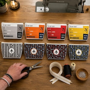Könnte beinhalten: Eine Sammlung von Reißverschlusstaschen zum Thema Reisen und Nähzubehör auf einer Holzoberfläche. Die Taschen haben Designs, die Flugtickets und Flughafen-Codes in verschiedenen Farben ähneln. Im Hintergrund befindet sich eine Singer-Nähmaschine.