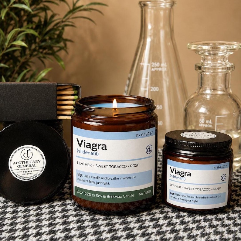 May include: Two amber glass jars containing soy and beeswax candles with labels reading Viagra, leather, sweet tobacco, and rose. The larger candle is 8 oz (226 g). A black matchbox with wooden matches and two clear glass laboratory vessels are present.
