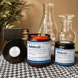 May include: Two amber glass candle jars with white labels reading Adderall C-II, Mixed Amphetamine Salts, Peppermint, Eucalyptus, Pine, White Pepper, 8 oz (226 g) Soy & Beeswax Candle. A black matchbox with a round Apothecary General logo label.