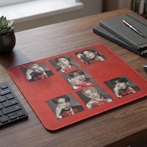 May include: A rectangular red mouse pad featuring six distinct black and white photographic portraits of individuals arranged in a grid pattern. Each portrait includes a small red circular graphic element. The mouse pad has rounded corners and a smooth surface.