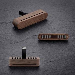 May include: Three rectangular wooden car air freshener vent clips made of dark brown wood. Each piece features a horizontal slot or a series of vertical ventilation slats and includes a black plastic clip attachment for mounting to a vehicle vent.