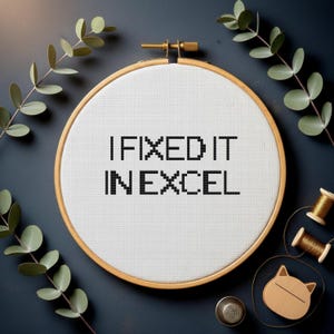 Könnte beinhalten: Ein Kreuzstich-Stickrahmen mit dem Text "I FIXED IT IN EXCEL" in Schwarz. Der weiße Stoff ist in einem Holzrahmen gespannt. Das Bild ist mit Zweigen, Garnrollen, einem Fingerhut und einem katzenförmigen Holzobjekt dekoriert.