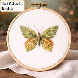 May include: A hand-embroidered butterfly design on white fabric, stretched within a wooden embroidery hoop. The butterfly features detailed stitching in shades of green, yellow, and brown, with the text "Hand Embroidered Template" in the upper left corner.