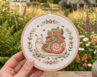 May include: A hand embroidery pattern in a wooden hoop. The design features a snail carrying a house on its back, surrounded by flowers and bees. The text "Hand Embroidery Pattern" is at the top.