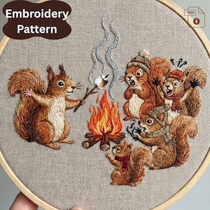 May include: Embroidery pattern featuring a group of squirrels gathered around a campfire. One squirrel holds a marshmallow on a stick. The squirrels are wearing hats and scarves. The text "Embroidery Pattern" is in a brown oval.