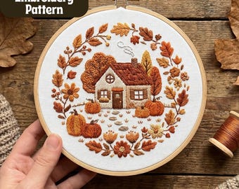 Puede incluir: Patrón de bordado a mano con una casa, calabazas y hojas de otoño. El diseño está en un aro de madera. El texto "Hand Embroidery Pattern" está en un óvalo verde oscuro. Mide unos 20 cm de diámetro.
