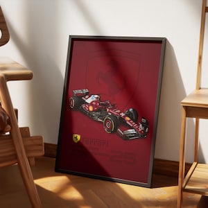 Puede incluir: Póster enmarcado con un coche de carreras Ferrari de Fórmula 1 rojo. El póster tiene un fondo rojo oscuro con el logotipo y el texto de Ferrari. El coche está detallado con detalles en rojo, negro y blanco, y las ruedas son amarillas.