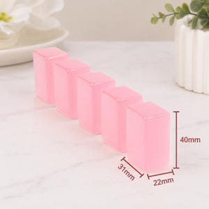 May include: Five translucent pink rectangular blocks, each approximately 1.2 inches tall, 0.9 inches wide, and 0.8 inches deep. The blocks are arranged in a row, with a white background and a small plant in a white pot.
