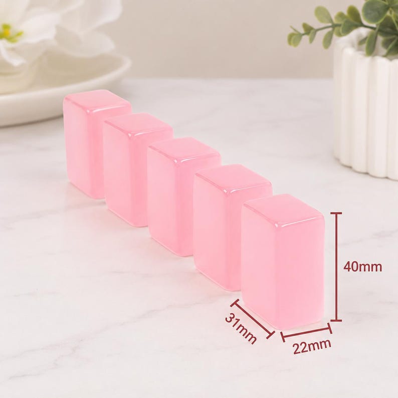 May include: Five translucent pink rectangular blocks, each approximately 1.2 inches tall, 0.9 inches wide, and 0.8 inches deep. The blocks are arranged in a row, with a white background and a small plant in a white pot.
