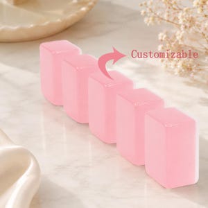 May include: Five pink, rectangular objects are arranged in a row. The objects have a smooth, glossy appearance. The word "Customizable" is written in red next to the objects. The background is a light, neutral color.