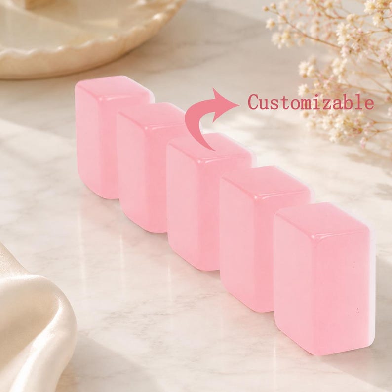 May include: Five pink, rectangular objects are arranged in a row. The objects have a smooth, glossy appearance. The word "Customizable" is written in red next to the objects. The background is a light, neutral color.
