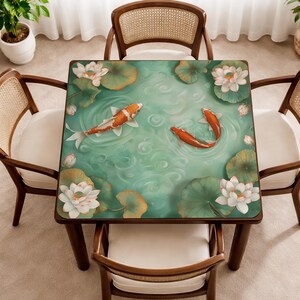 May include: Square wooden table with a painted top featuring a pond scene with koi fish, lily pads, and lotus flowers. The table is surrounded by four wooden chairs with woven backs and white cushions.