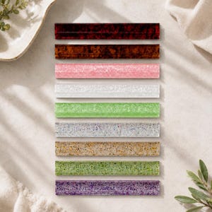 May include: An assortment of rectangular decorative items in various colors, including shades of brown, pink, white, green, and purple. Each item has a textured surface and a glossy finish, arranged neatly on a light-colored surface.