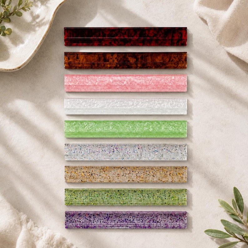 May include: An assortment of rectangular decorative items in various colors, including shades of brown, pink, white, green, and purple. Each item has a textured surface and a glossy finish, arranged neatly on a light-colored surface.