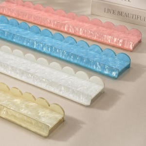 May include: Four decorative trays in pastel colors: pink, blue, white, and yellow. Each tray has a scalloped edge and a rectangular base. The trays are made of a translucent material, and the text "LIVE BEAUTIFUL" is visible in the background.