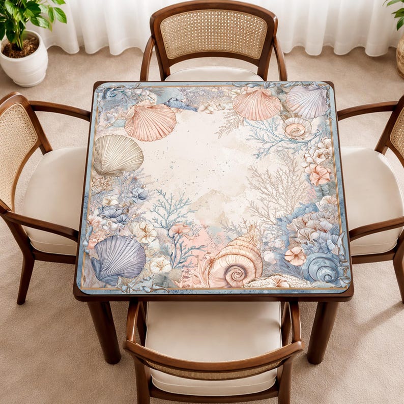 May include: A square table featuring a printed surface with a detailed marine-themed illustration. The design displays various seashells, coral formations, and sea plants in soft shades of blue, pink, and beige, arranged in a border pattern.