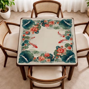 Puede incluir: Una mesa cuadrada con una superficie de color crema decorada con un borde de flores de loto rojas, nen&uacute;fares de color verde oscuro y peces koi naranjas y blancos. La mesa se apoya sobre cuatro patas de madera y tiene cuatro sillas.