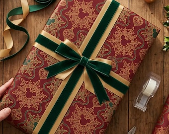 Könnte beinhalten: Ein rechteckiges Geschenk, eingewickelt in dunkelrotes Papier mit goldenem Schneeflockenmuster und versteckten Mickey-Mouse-Silhouetten. Das Paket ist mit einem dunkelgrünen Samtband und einem goldenen Satinband als Schleife verziert.