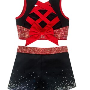 Peut inclure: Ensemble d'uniforme de cheerleading noir et rouge. Le haut pr&eacute;sente un design crois&eacute; dans le dos avec un n&oelig;ud rouge. Le haut et le short sont orn&eacute;s de strass. Le short est noir avec un d&eacute;grad&eacute; de strass.