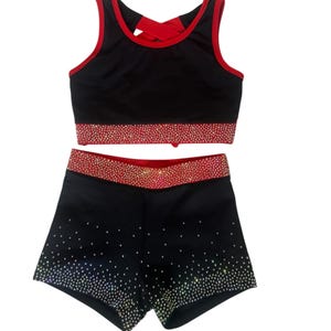 Peut inclure: Ensemble d'uniforme de cheerleading noir avec garniture rouge et embellissements scintillants. Le haut est un crop top avec un n&oelig;ud rouge dans le dos. Le short a une ceinture rouge assortie et est recouvert de strass scintillants.