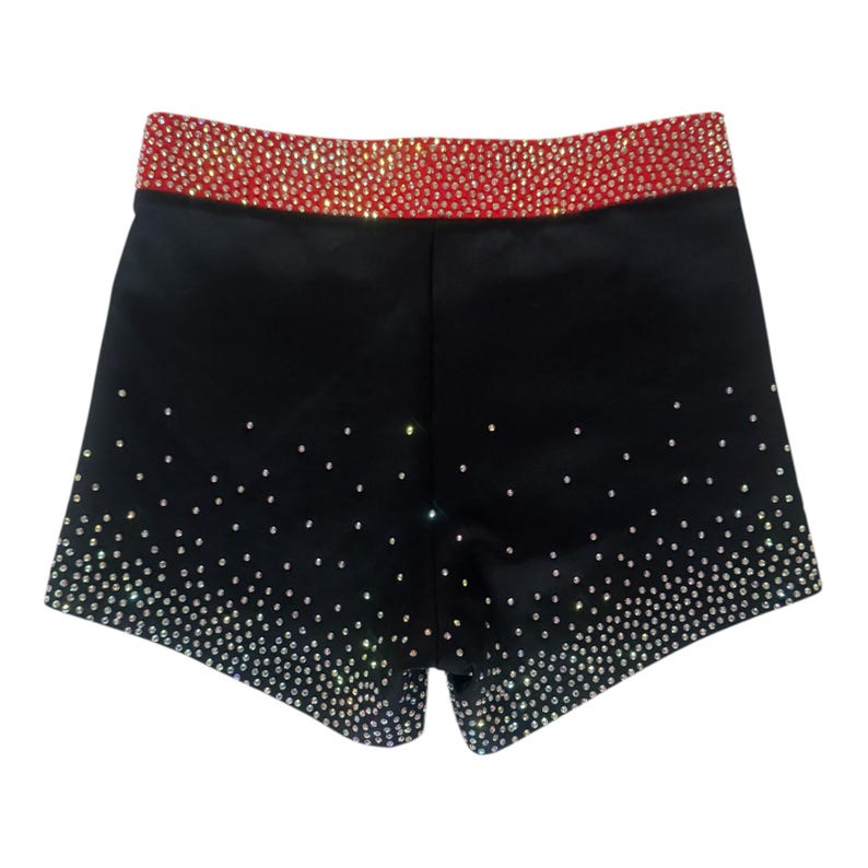 Peut inclure: Shorts de sport noirs avec une ceinture rouge. Les shorts sont orn&eacute;s de strass scintillants qui s'estompent de l'ourlet inf&eacute;rieur vers le haut. La ceinture est enti&egrave;rement recouverte de strass.
