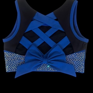 Peut inclure: Haut de sport bleu et noir avec un n&oelig;ud et des strass. Le haut pr&eacute;sente un motif crois&eacute; dans le dos et un n&oelig;ud &agrave; l'avant. Des strass sont plac&eacute;s &agrave; l'avant et sur les c&ocirc;t&eacute;s du haut.