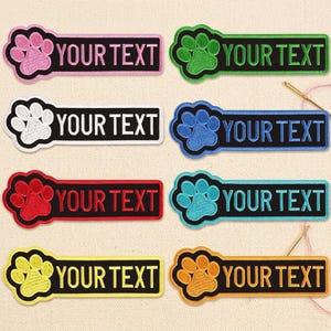 May include: Embroidered patches in various colors, featuring a paw print design and the text "YOUR TEXT" in white. The patches have a black rectangular background and are ideal for pet owners.
