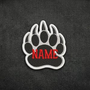 May include: Embroidered patch in the shape of a bear paw with the word "NAME" in red. The paw print is black with a white outline and is set against a dark gray textured background.