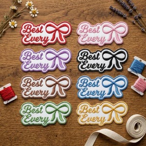 May include: Eight embroidered patches featuring the text Best Every and a bow icon in red, pink, purple, black, brown, blue, green, and yellow. Each patch has a white background and a scalloped border, accompanied by spools of thread and ribbon.