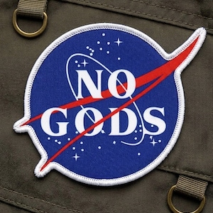 May include: A circular patch with a blue background and the words "NO GODS" in white, crossed out by a red diagonal line. The patch has a white border and is set against a green fabric background.