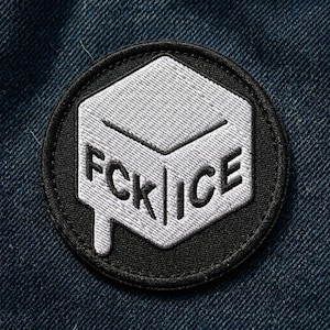 May include: Embroidered patch with the text "FCK ICE" in white on a black and gray geometric design. The patch is circular and set against a blue denim background.
