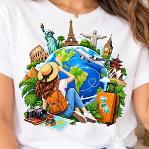 May include: A white t-shirt featuring a colourful graphic of a globe surrounded by world landmarks including the Statue of Liberty, Eiffel Tower, and Big Ben. A traveller with a backpack, camera, and orange suitcase sits before the globe.