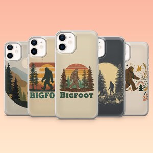 May include: A collection of five phone cases with Bigfoot-themed designs. The cases feature illustrations of Bigfoot in various outdoor settings, including forests and sunsets. The color palette includes earth tones, with text that reads "BIGFOOT".