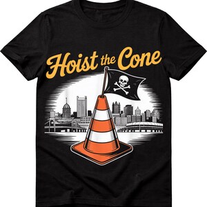 May include: Black t-shirt with a graphic featuring an orange and white traffic cone with a skull and crossbones flag, the text "Hoist the Cone", and a city skyline.