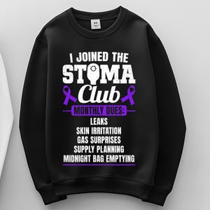 May include: Black sweatshirt with white text that reads "I JOINED THE STOMA Club" with purple ribbon graphics. Below the text are the words "MONTHLY DUES: LEAKS SKIN IRRITATION GAS SURPRISES SUPPLY PLANNING MIDNIGHT BAG EMPTYING."