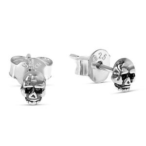 Könnte beinhalten: Zwei kleine Ohrstecker mit silbernen Totenkopf-Motiven. Jeder Ohrring zeigt ein detailliertes Totenkopf-Design mit Augenhöhlen, Nasenhöhle und Kieferlinie. Die Ohrringe sind vor einem weißen Hintergrund platziert, was ihre komplizierten Details und ihren metallischen Glanz hervorhebt.