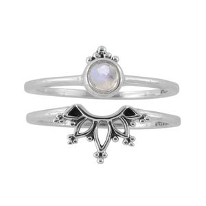 May include: Two silver rings. The top ring features a small, round, iridescent stone. The bottom ring has a decorative, curved design with small, beaded accents. Both rings have a thin band.