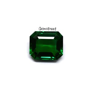May include: Emerald-cut, deep green gemstone with a faceted surface. The gemstone is set against a white background. The word "Gemstreet" is printed in black cursive text.