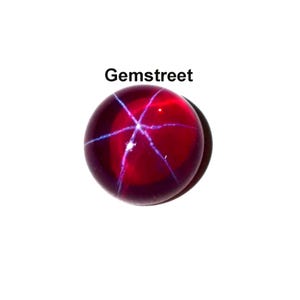 May include: A round, deep red gemstone with a star-like pattern of white lines radiating from the center. The gemstone has a polished surface and is set against a white background. The text "Gemstreet" is above the gemstone.