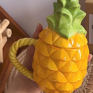 Może przedstawiać: Biały ceramiczny kubek z czarnym uchwytem i napisem "But First, Coffee" pogrubioną, czarną czcionką. Kubek jest ustawiony na gładkim, białym tle.